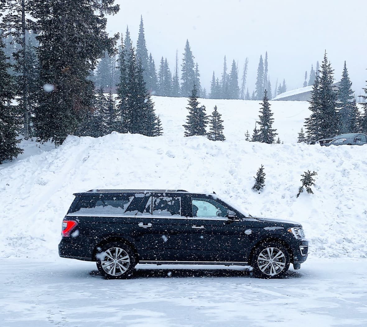 Black Ford Expedition MAX parked in fresh snow among pine trees